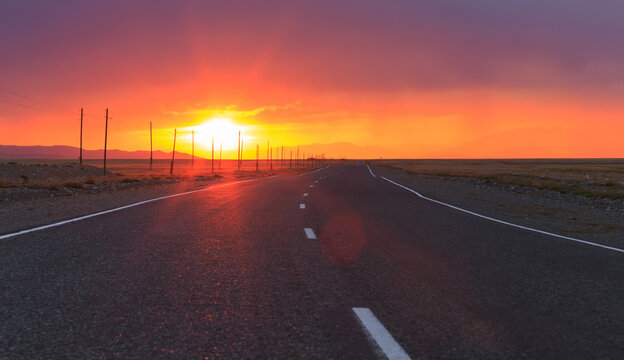 Red amazing sunset over an infinitely long asphalt road in the Altai Republic on the border with Mongolia