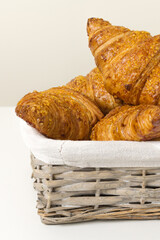 tasty croissants in wicker basket on white background. French food. Close up