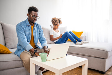 Obraz premium Millennial generation father working from home with small children while in quarantine isolation during the Covid-19 health crisis. Little girl on tablet computer. 