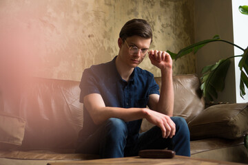 Fashion portrait of a handsome young man sitting on the sofa with a confident look on his face.