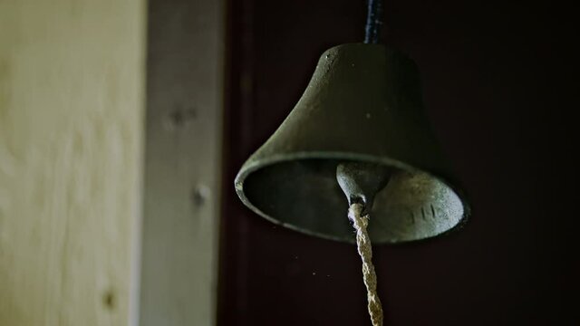 Slow motion video of a human hand ringing a bell. The subject is a bell that gives a signal in the box or at school.