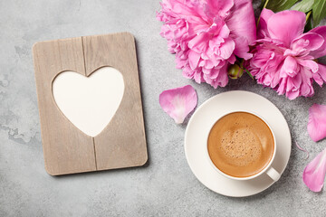 Hot coffee, peony flowers and heart shaped frame