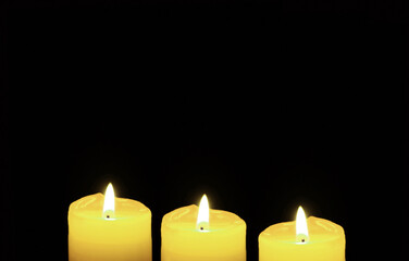 Shining Three of Yellow Candles on Black Backdrop with Copy Space