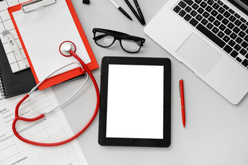 Tablet computer with stethoscope and accessories of doctor on grey background
