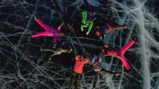 The drone takes off spinning around its axis, a view of the ice opens with tourists lying and making synchronized movements. 
