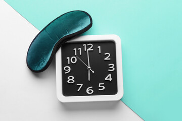 Stylish clock and sleeping mask on color background