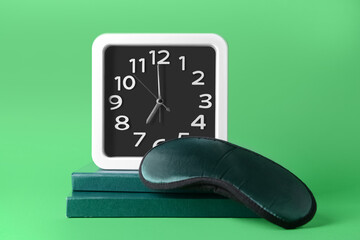 Stylish clock, books and sleeping mask on color background