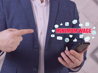  MINIMUM WAGE phrase on the screen. Loan officer use cell technologies at office. A minimum...