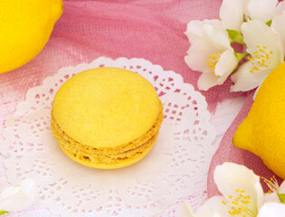 Obraz na płótnie Canvas yellow macaroon cake on a pink background with a fresh lemons. Lemon macaroon with yellow cream. Round delicious dessert with lemon flavor. High quality photo
