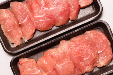 Turkey fillet in a black plastic container isolated.