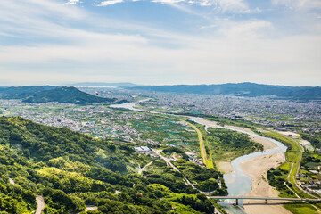 梅雨晴れの中、紀の川上空を飛ぶパラグライダーから和歌山市街と和歌山湾を望む