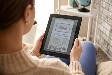 Woman holding tablet computer with open page of delivery service application at home, closeup
