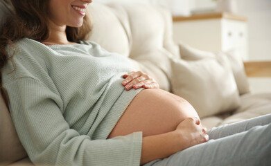 Obraz na płótnie Canvas Pregnant woman touching her belly indoors, closeup
