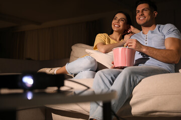 Obraz premium Couple watching movie with popcorn on sofa at night, space for text