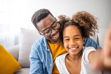 Smiling black father and child daughter taking selfie together looking at camera, head shot...