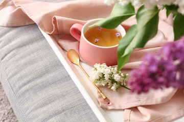 Obraz na płótnie Canvas Cup of tea with spoon and lilac flowers, closeup
