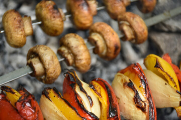 Appetizing grilled vegetables skewers: mushrooms, onions and red bell peppers.