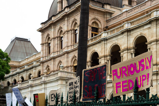 Protest signs on a fence outside a grand old sandstone building