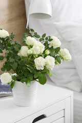 Beautiful white rose in pot on table in bedroom