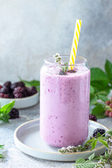 Natural healthy detox, fruit dessert, healthy dieting concept. Blackberry milk shake or Yogurt smoothie in glass jar on a light stone tabletop.