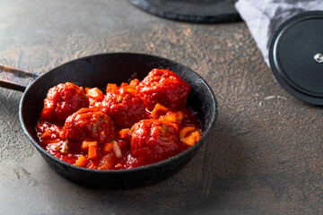 Popular Spanish dish Albondigas or Meatballs  with tomato sauce  in frying pan  on dark background.
