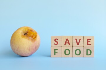 Save food concept. Apple scrap with wooden blocks typography in blue background with copy space.