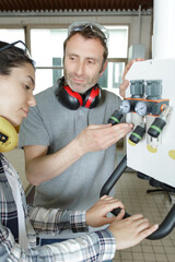 engineer explaining industrail machine to apprentice