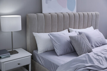 Cozy bed with soft silky bedclothes in light room