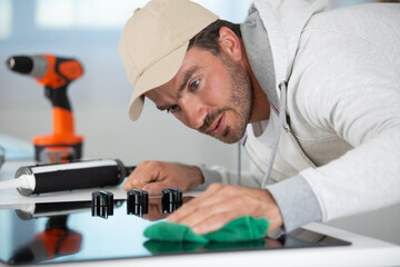 young repairman installing induction cooker in kitchen