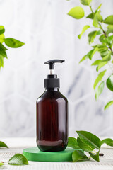 Organic cosmetic product in a brown dispenser on a background of green leaves. Eco friendly product.