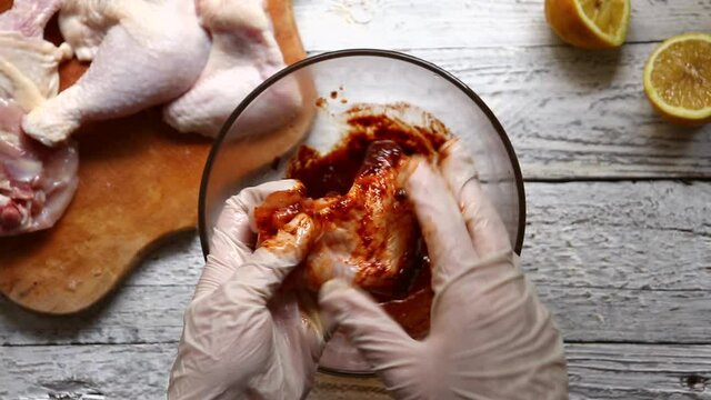 A woman marinates meat for a barbecue. The chef marinates chicken wings. Top view. Cooking in the kitchen.