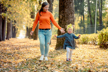 Fototapeta premium cute baby girl with mom in the park. beautiful autumn in the park