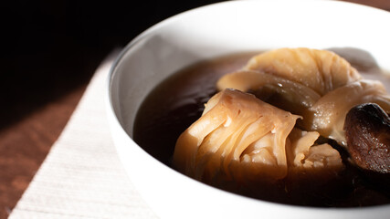 The traditional food of Asia, Boiled cabbage and Shiitake soup with the soy sauce in the white bowl place on the wooden table