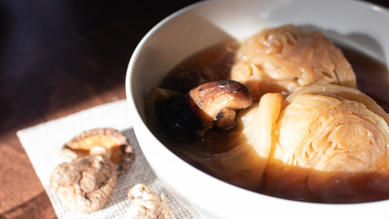 The traditional food of Asia, Boiled cabbage and Shiitake soup with the soy sauce in the white bowl with dried shiitake and all place on the wooden table