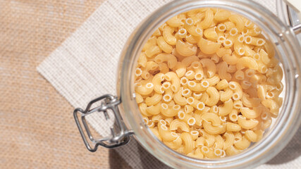 The opened macaroni's bottle with the natural light place on the burlap hessian with the copy space on the left side