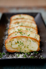 Tasty bread with garlic, cheese and herbs on kitchen table