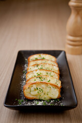 Tasty bread with garlic, cheese and herbs on kitchen table