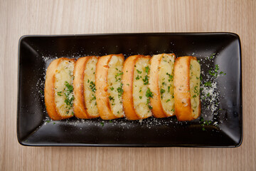 Tasty bread with garlic, cheese and herbs on kitchen table