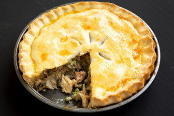 Homemade Chicken Pot Pie on a black surface, side view. Close-up.