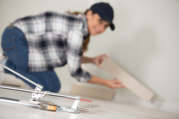 handywoman fitting tile which has been cut with tile cutter