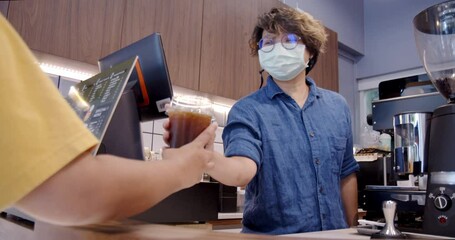 Asian non-binary owner happily making coffee for a customer in own coffee shop. Slow Motion - Authentic LGTBQ+ inclusive moments in community and local business, pride month concept.