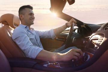 Businessman driving luxury convertible car outdoors on sunny day - obrazy, fototapety, plakaty