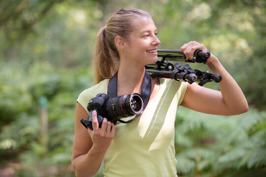 Female Photographer Carries Tripod On Her Shoulder