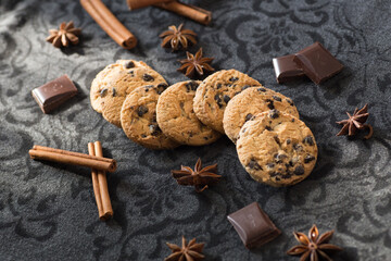a few cookies with chunks of chocolate on a dark background surrounded by decor