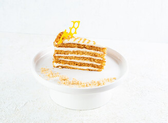 Honey cake based on buckwheat and lime honey with cream. On a white plate Light background.