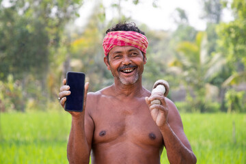 Rural Indian Man Showing on mobile phone in agricultural field