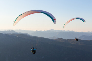 Paragliding couple flying in sunset over the mountains