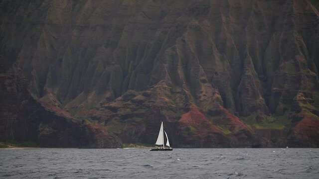 Vessel sailing along dramatic Na Pali Coast in Kauai, Hawaii. Mid angle, parallax movement, HD.