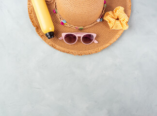 Summer lady straw hat, yellow sun protection spray and sunglasses on turquoise stone background.