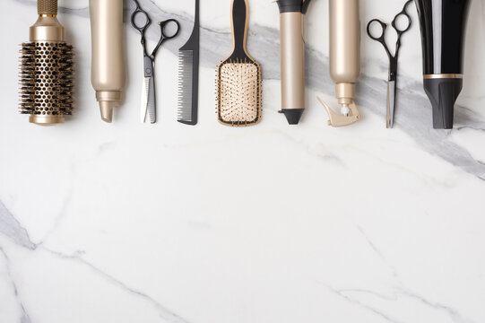 Collection of professional hair dresser tools arranged on marble background